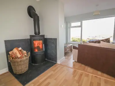a living room with a fireplace and a couch at Crantock Bay House in Crantock