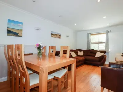 a dining room with a table and chairs and a couch at The Dunes in Crantock