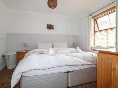 a white bedroom with a large bed with white sheets at The Dunes in Crantock