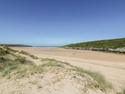 a beach with people walking on the sand at The Dunes in Crantock