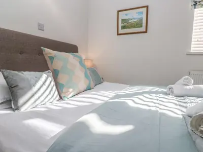 a bed with white sheets and pillows in a bedroom at Kittiwake in Crantock