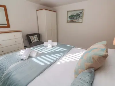 a bedroom with a large white bed with a chair at Kittiwake in Crantock