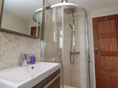 a bathroom with a white sink and a shower at Kittiwake in Crantock