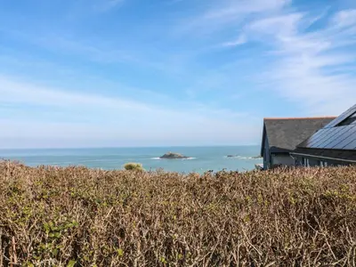a house on a hill with the ocean in the background at Kittiwake in Crantock