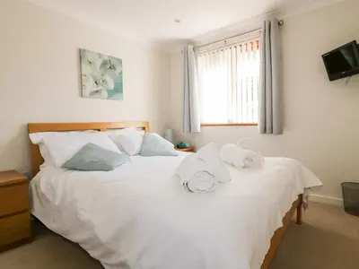 a bedroom with a large white bed with towels on it at Carpe Diem in Crantock