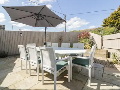 a white table and chairs with an umbrella at Carpe Diem in Crantock