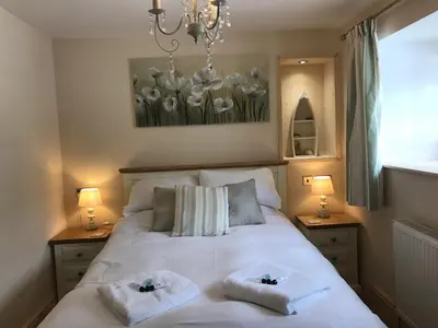a bedroom with a white bed with two towels on it at The Waterwheel in St Austell