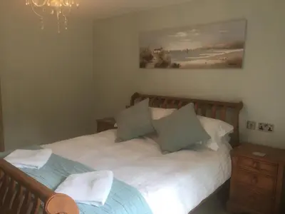 a bedroom with a white bed with a wooden headboard at The Waterwheel in St Austell