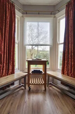 a room with a table and two benches in front of a window at Roselyn House in Par
