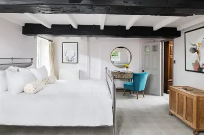 a bedroom with a white bed and a blue chair at The Hideaway & Spa Terrace at Tregoose Old Mill in Newquay