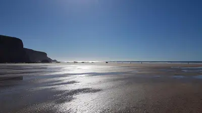 a view of a beach with the ocean in the background at The Hideaway & Spa Terrace at Tregoose Old Mill in Newquay