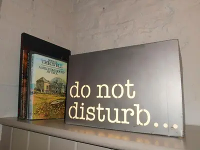 a shelf with two books and a sign that says do not disturb at The Hideaway & Spa Terrace at Tregoose Old Mill in Newquay