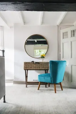 a mirror and a blue chair in front of a table at The Hideaway & Spa Terrace at Tregoose Old Mill in Newquay