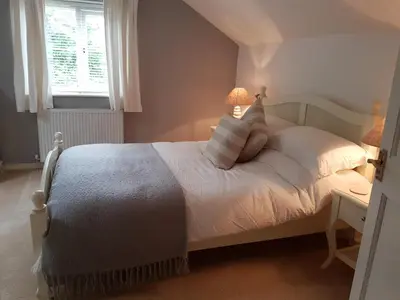 a bedroom with a bed with white sheets and a window at The Beekeeper's Cottage in Saint Columb Major