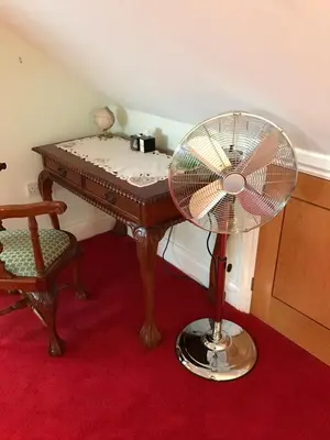 a fan sitting next to a table with a desk at Orchard Manor in Probus