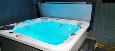 a bath tub filled with blue water in a room at Romantic Hot Tub Breaks Marthys House Looe Polperro Talland Bay in Looe