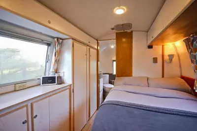a small room with a bed and a window at Vintage glamping Airstream with Farm Animals in Penryn