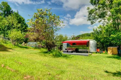 a red and silver trailer parked in a field at Vintage glamping Airstream with Farm Animals in Penryn