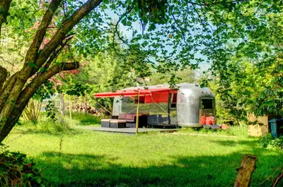 a red and silver trailer parked in a field at Vintage glamping Airstream with Farm Animals in Penryn