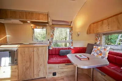 a red couch and a table in a caravan at Vintage glamping Airstream with Farm Animals in Penryn