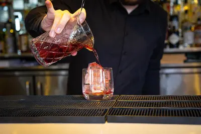 a person pouring a drink into a glass at Mannings Hotel in Truro