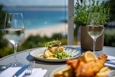 a table with a plate of food and two glasses of wine at Harbour Hotel & Spa St Ives in St Ives