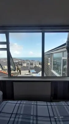 a room with a window with a view of the ocean at OYO Shore Surf Lodge in Newquay