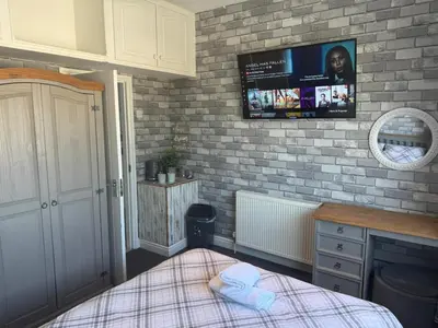 a bedroom with a bed and a tv on a brick wall at OYO Shore Surf Lodge in Newquay