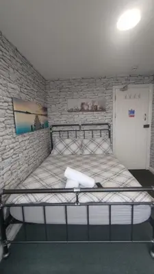 a bed in a room with a brick wall at OYO Shore Surf Lodge in Newquay