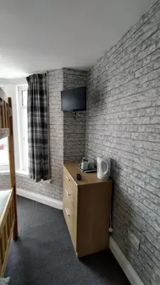 a bedroom with a brick wall and a wooden dresser at OYO Shore Surf Lodge in Newquay