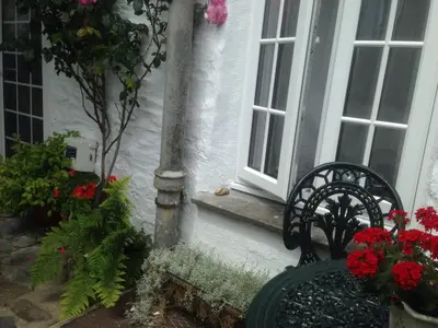 a bench sitting in front of a house with flowers at Central Boscastle studio flat in Boscastle