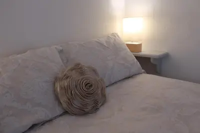 a pillow sitting on a bed next to a lamp at Central Boscastle studio flat in Boscastle