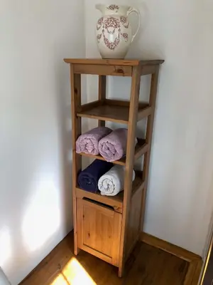 a wooden shelf with towels and a vase on it at Central Boscastle studio flat in Boscastle