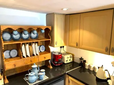 a kitchen with wooden cabinets and a counter top at Central Boscastle studio flat in Boscastle