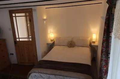 a small bedroom with a bed and two lamps at Central Boscastle studio flat in Boscastle