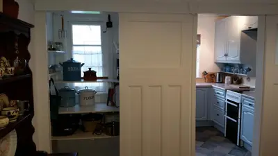 an open door to a kitchen with white cabinets at Sunways in Padstow