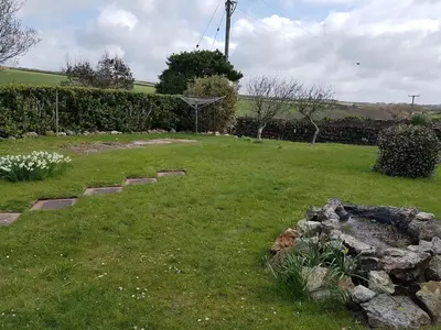 a garden with a rock fire pit in the grass at Sunways in Padstow
