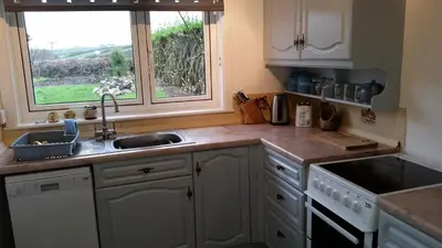 a kitchen with white cabinets and a sink and a window at Sunways in Padstow