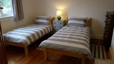 two beds in a room with a lamp on a table at Sunways in Padstow