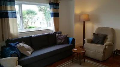 a living room with a couch and a chair and a window at Sunways in Padstow