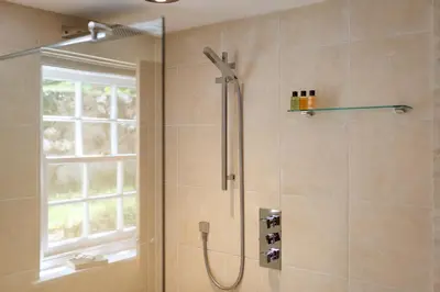 a shower in a bathroom with a window at The Home Barn at Cornish Barn Holidays in Perranwell