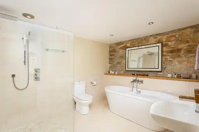 a bathroom with a tub and a toilet and a sink at The Home Barn at Cornish Barn Holidays in Perranwell