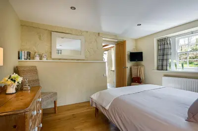 a bedroom with a bed and a desk and a mirror at The Home Barn at Cornish Barn Holidays in Perranwell