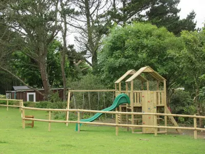 a wooden playground with a slide in a park at Mount Hawke Holiday Bungalows in Porthtowan