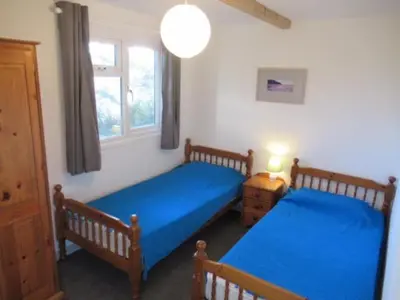 a bedroom with two beds with blue sheets and a window at Mount Hawke Holiday Bungalows in Porthtowan
