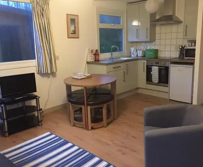 a kitchen with a table and a small table in a room at Mount Hawke Holiday Bungalows in Porthtowan