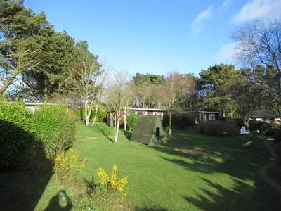 a garden with trees and a house in the background at Mount Hawke Holiday Bungalows in Porthtowan