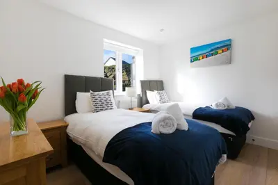 a bedroom with two beds and a vase of flowers at Tara in St Ives
