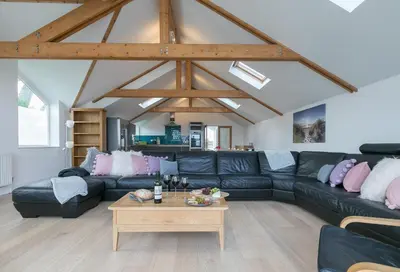 a living room with a black leather couch and a table at Tara in St Ives