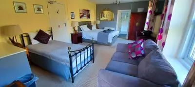 a living room with a couch and a bedroom with two beds at Sportsmans Valley Hotel in Liskeard